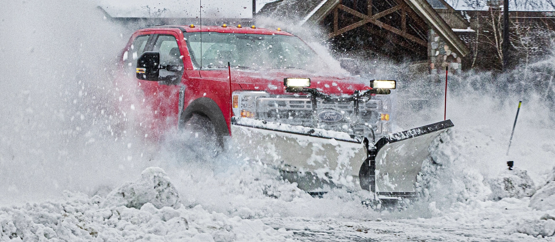 2026 Ford Super Duty® F-450® XLT truck in Race Red driving through heavy snow with snowplow equipment