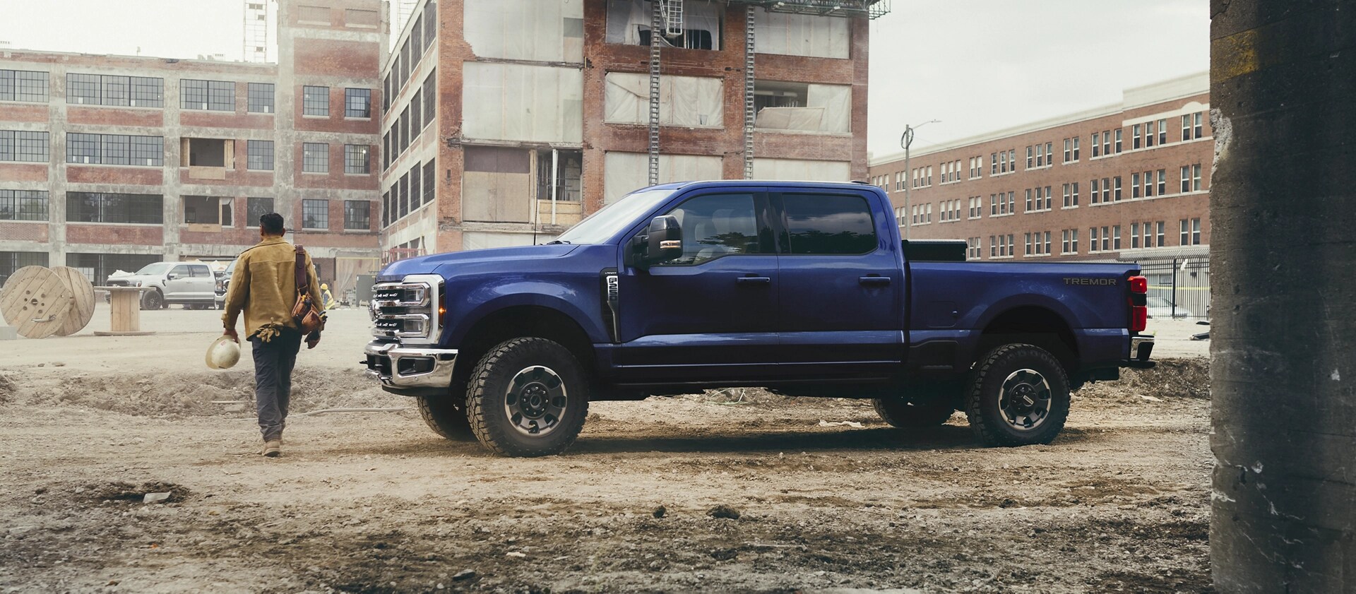 A person walking away from their 2026 Ford Super Duty® F-250® Lariat® model in Argon Blue on a construction site