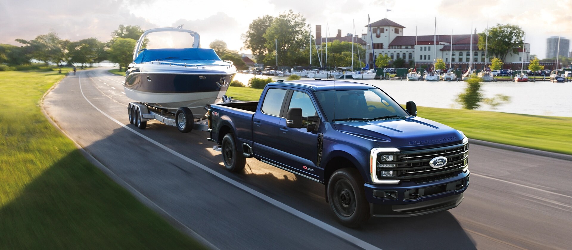 2026 Ford Super Duty® F-350® Platinum® model in Argon Blue towing a speed boat on a paved road