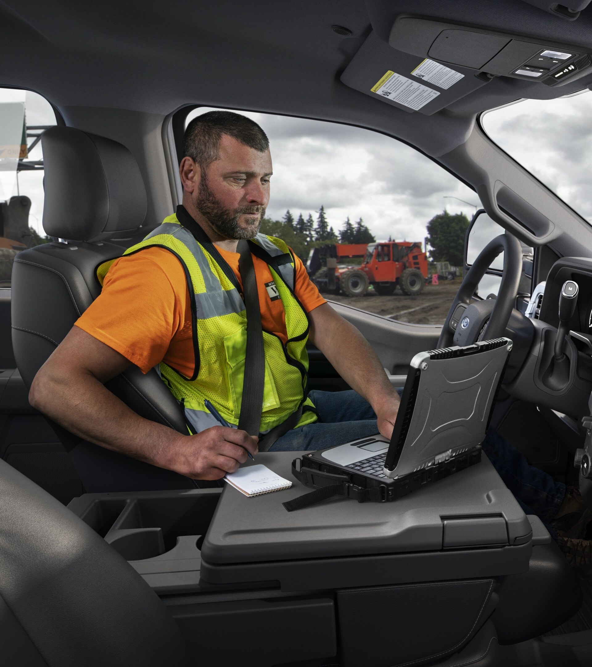 A person inside the cabin of their 2026 Ford Super Duty® using a laptop with the interior work surface