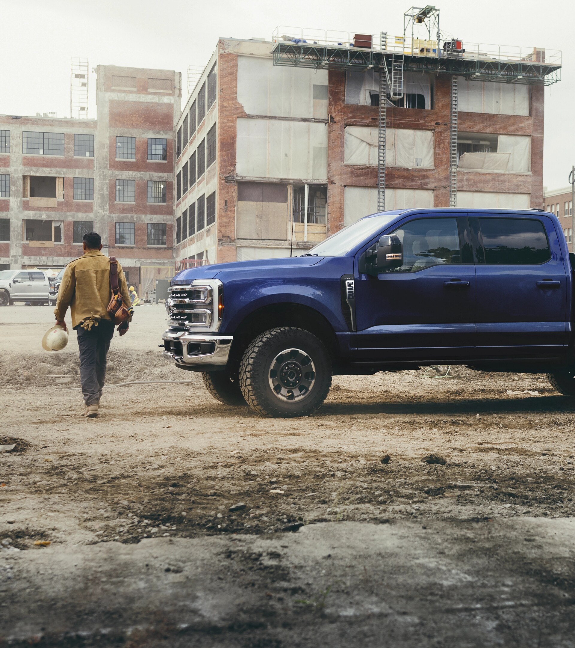 A person walking away from their 2026 Ford Super Duty® F-250® Lariat in Argon Blue on a construction site