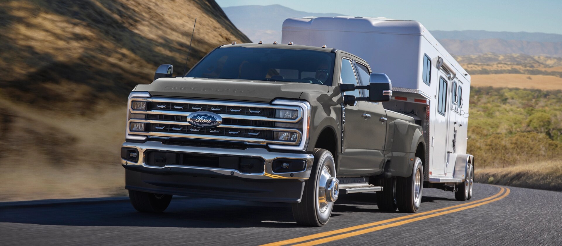 2026 Ford Super Duty® F-350® Lariat® model in Marsh Grey pulling a trailer on a paved road