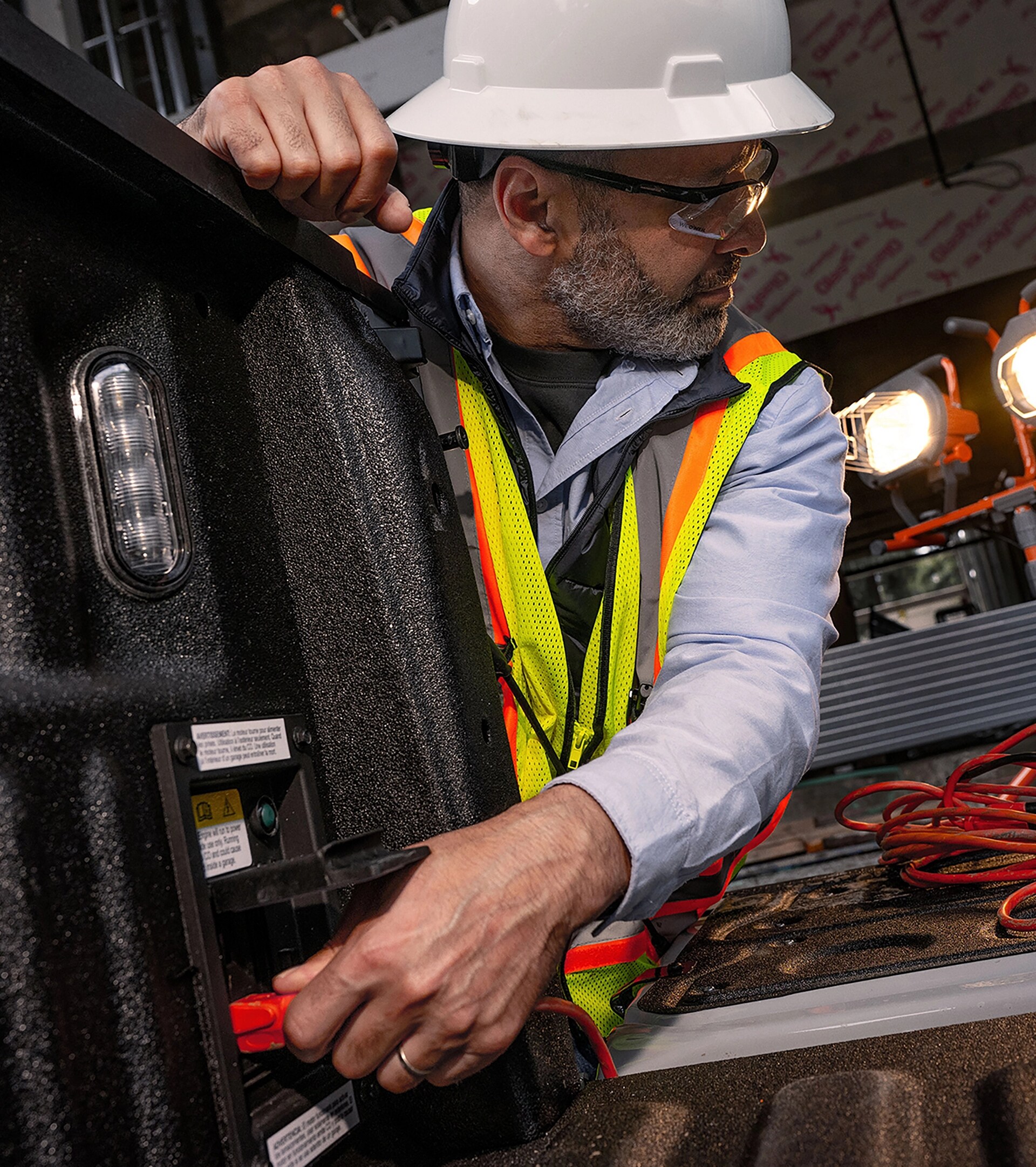 A male construction worker plugging into the Pro Power Onboard in a 2026 Ford Super Duty’s bed