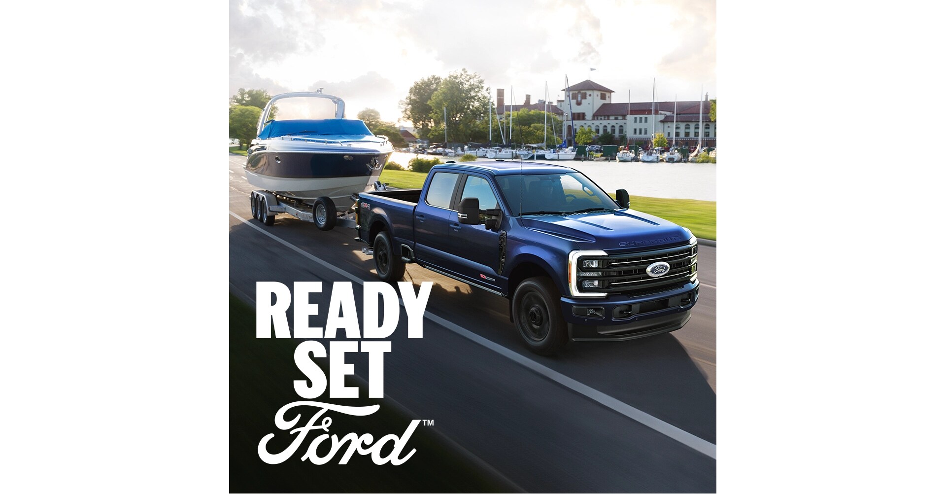A blue 2026 Ford Super Duty towing a boat. White text “Ready Set Ford” is in the lower right corner
