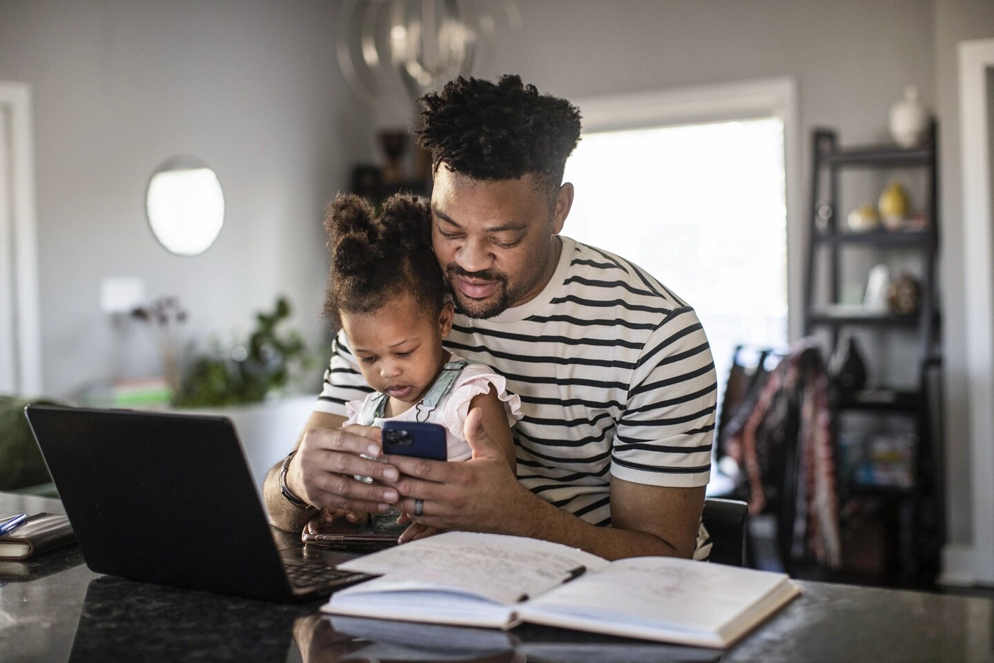 A man holds his child in his lap while interacting with the FordPass app on his phone