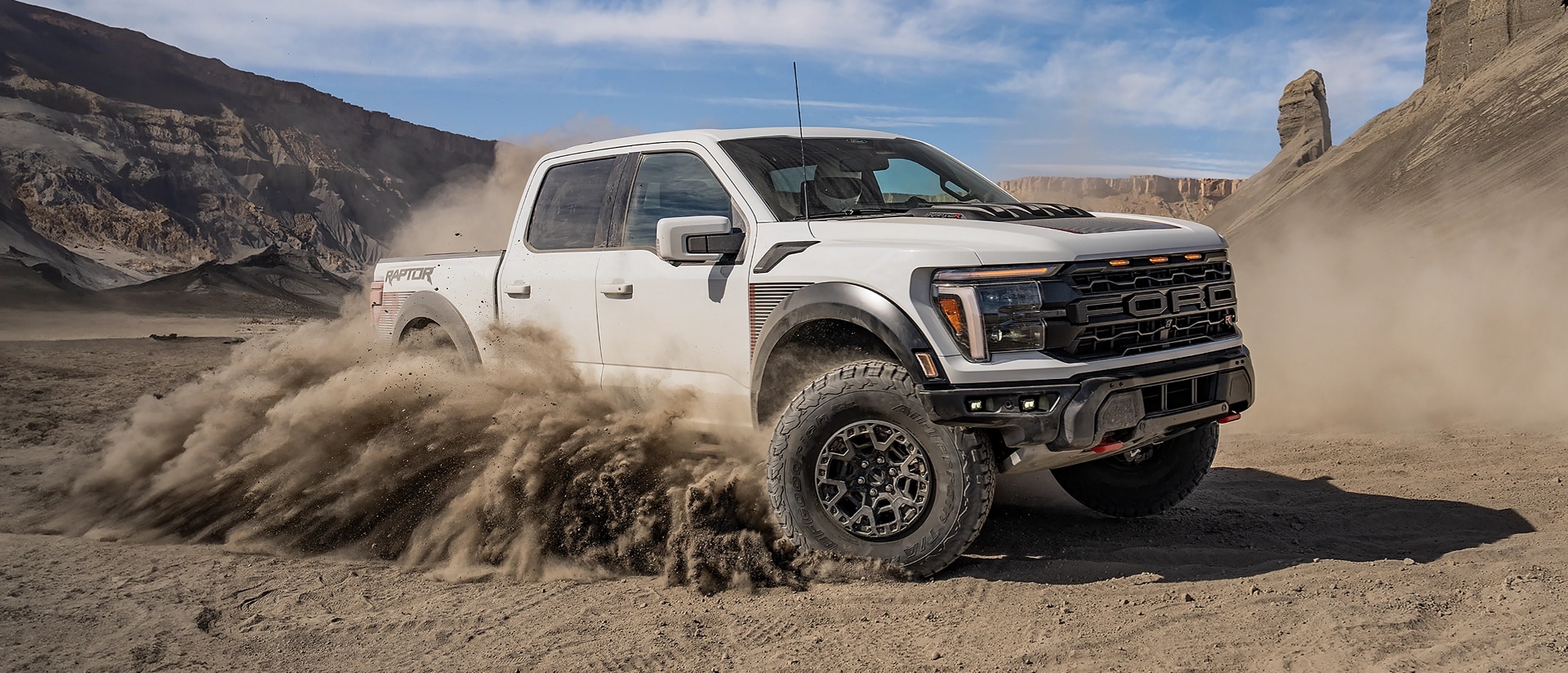 2025 F-150® Raptor® R™ truck racing across the desert leaving a trail of dust behind