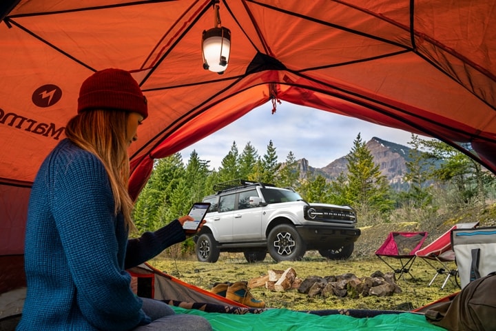 4-door 2023 Ford Bronco® Outer Banks™ seen through a tent where a person is camping