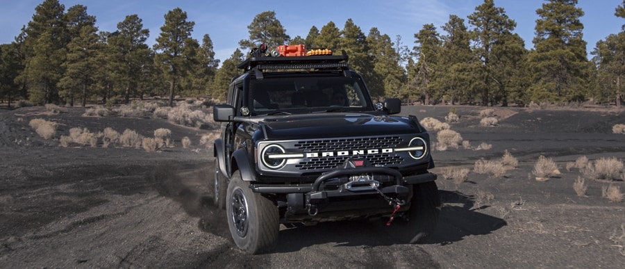 A 2-door 2023 Ford Bronco® Badlands® in Shadow Black being driven down a dirt road
