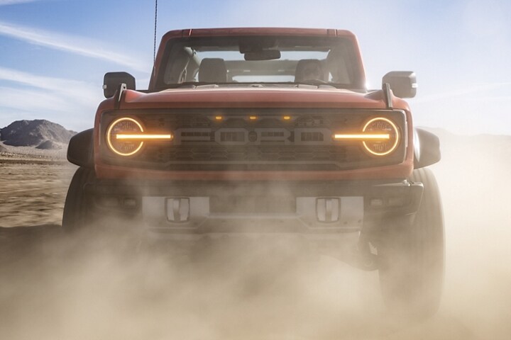 4-door 2023 Ford Bronco® Wildtrak™ model in Code Orange being driven in the desert with top removed