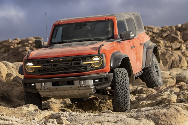 4-door 2023 Ford Bronco® Raptor® model shown in Code Orange being driven over rocks