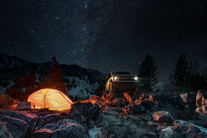 2-door 2023 Ford Bronco® Big Bend™ model in Oxford White parked by a campsite at night