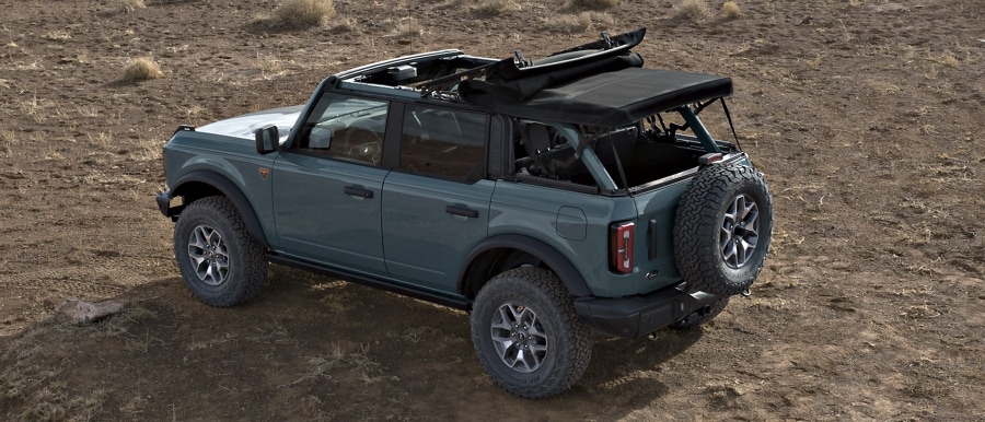 4-door 2024 Ford Bronco® Badlands™ shown in Azure Grey Metallic Tri-Coat with soft top roof half open and rear panel removed
