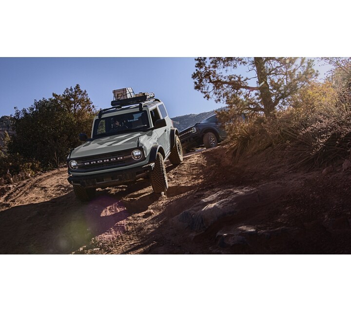Four-door 2024 Ford Bronco® Everglades™ being driven down a steep trail