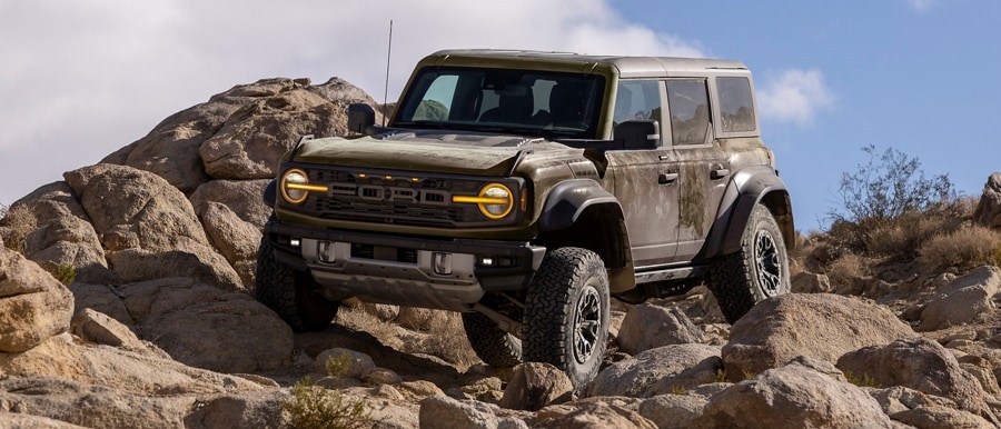 2024 Ford Bronco Raptor® in available Shelter Green being driven over huge rocks