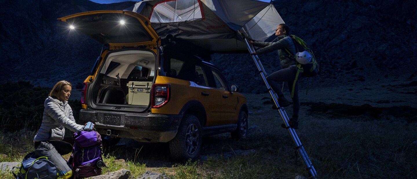A woman unpacking under the rear flood lights in a 2021 Ford Bronco Sport