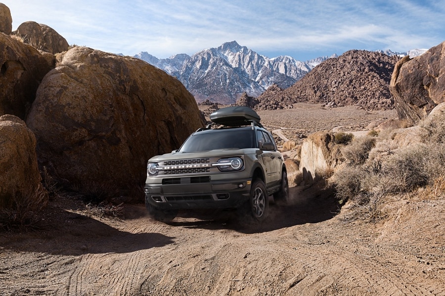 A 2023 Ford Bronco® Sport being driven on a dirt terrain with mountains in the background