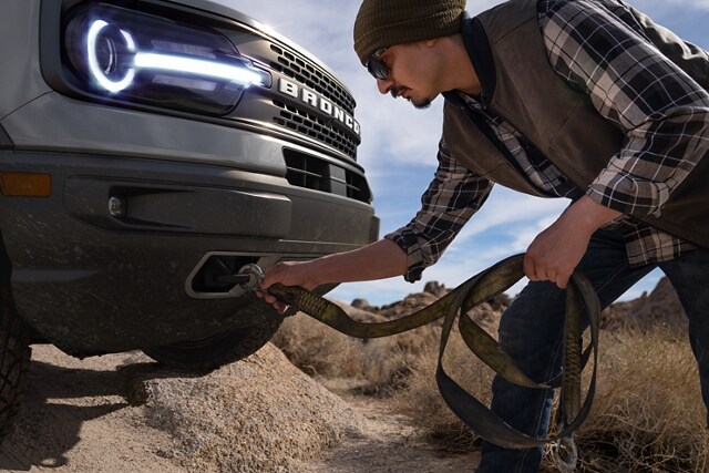 A man hooking a strap to the Front Tow Hooks