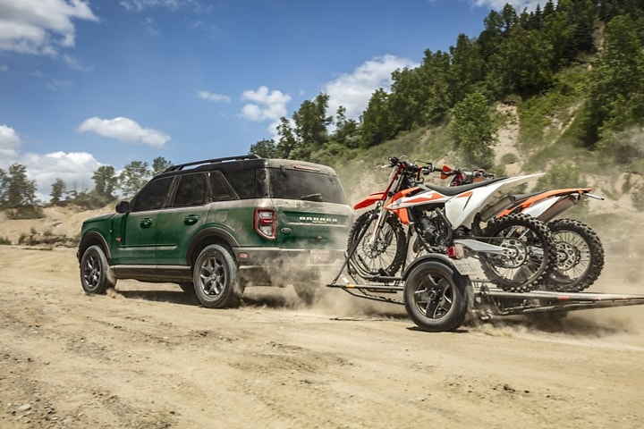 A 2023 Ford Bronco® Sport SUV towing two dirt bikes off-road