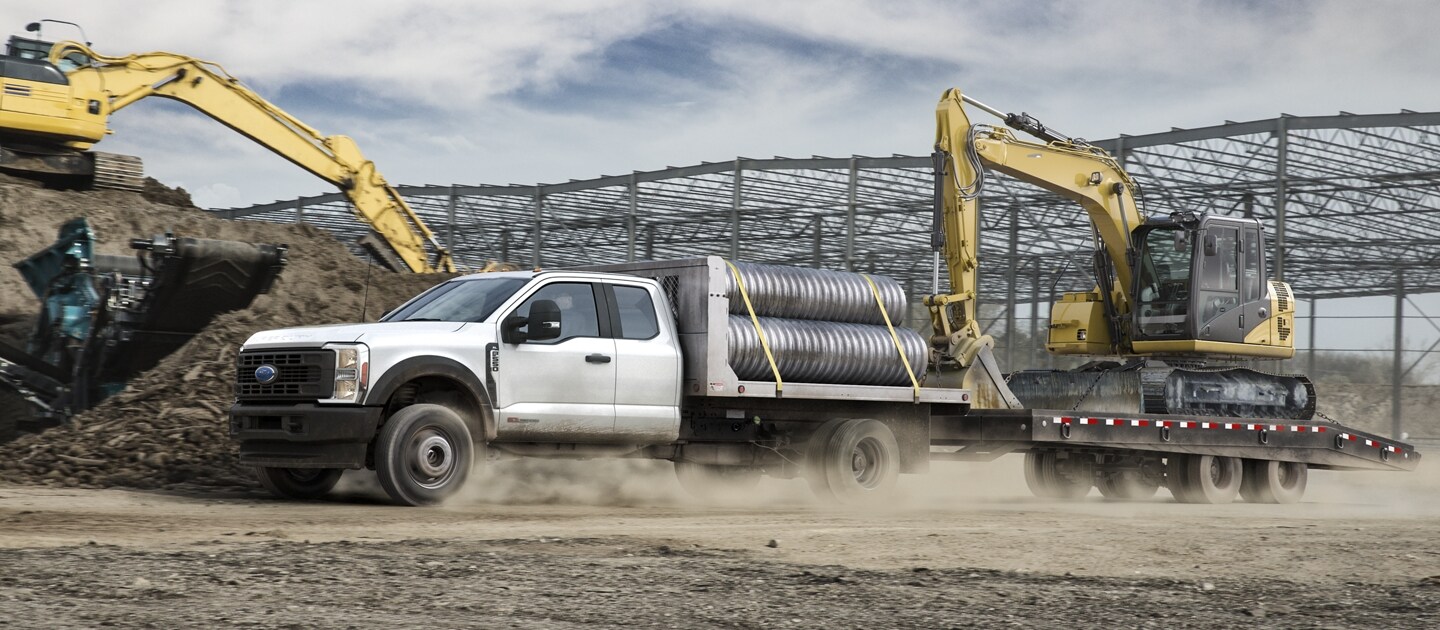 2023 Ford Super Duty® F-600 XLT Chassis Cab in Oxford White with bucket upfit parked in front of body shop