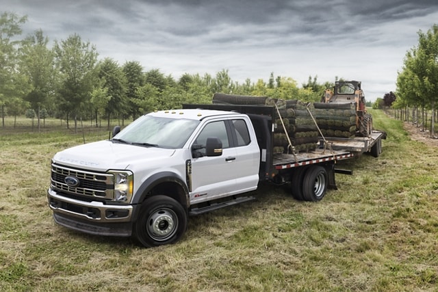 2023 Ford Super Duty® Chassis Cab with flatbed body and flatbed trailer being driven on road