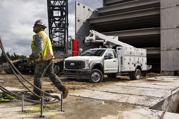 Construction workers working near 2023 Ford Super Duty® with crane upfit parked at work site