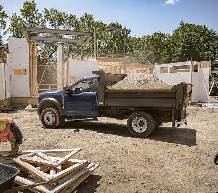Truck parked at a building site with dump upfit and a bed full of dirt