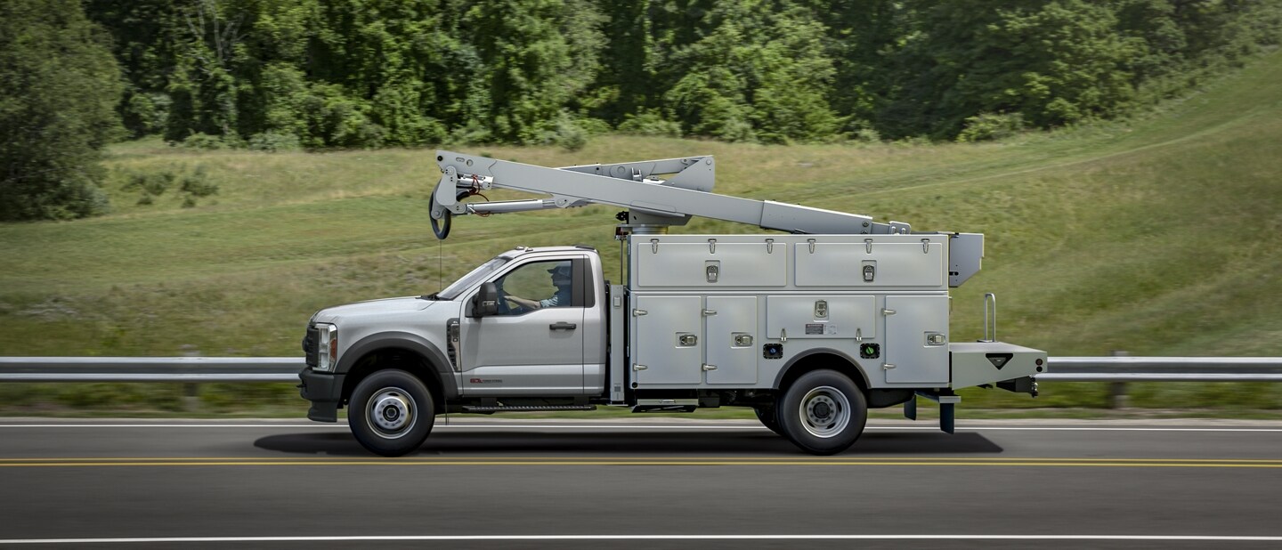 Side view of 2023 Ford Super Duty® Chassis Cab with upfit being driven on the road near grass and trees