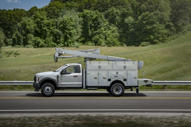 Side view of 2023 Ford Super Duty® Chassis Cab with upfit being driven on the road near grass and trees