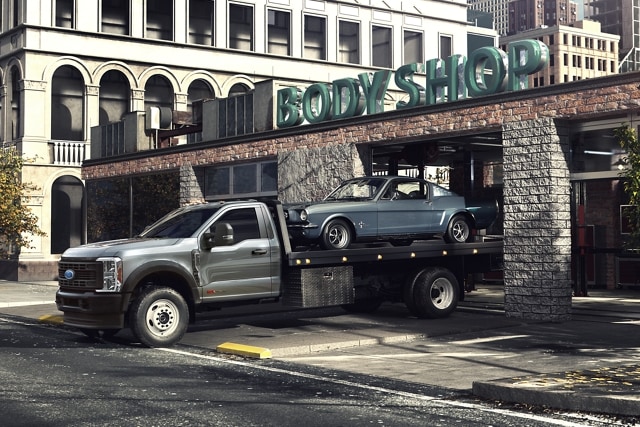 2023 Ford Super Duty® Chassis Cab pulling out of body shop garage with car on back flatbed
