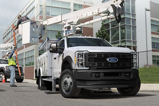Workers moving machinery near 2023 Ford Super Duty® Chassis Cab with upfit at work site