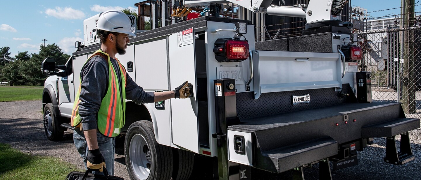 2023 Ford Super Duty® parked at the job site with a worker opening side panel