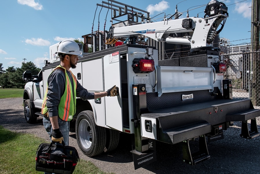 Rear of a 2025 Ford Super Duty® as a worker is opening a door on a utility box