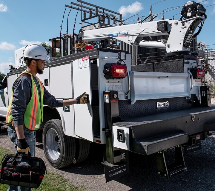 Worker standing outside a 2025 Ford Super Duty® Chassis Cab with crane uplift