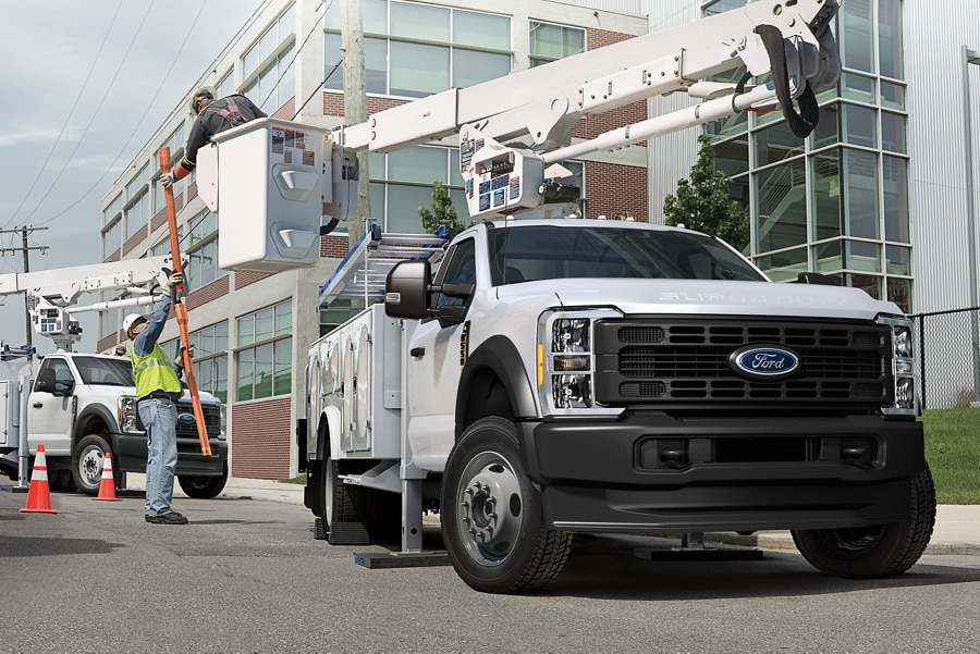 2025 Ford Super Duty® F-350® with a bucket upfit with a worker grabbing material from another worker