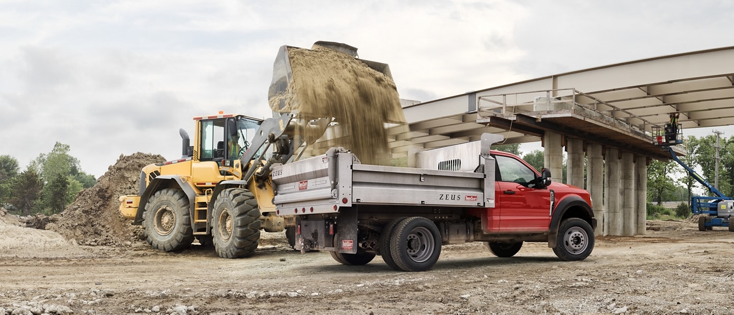 A 2025 Ford Super Duty® F-550® XL with a dump bed being filled with dirt