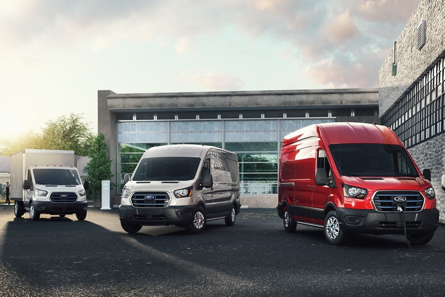 Three 2023 Ford E-Transit™ vehicles parked in front of an industrial building