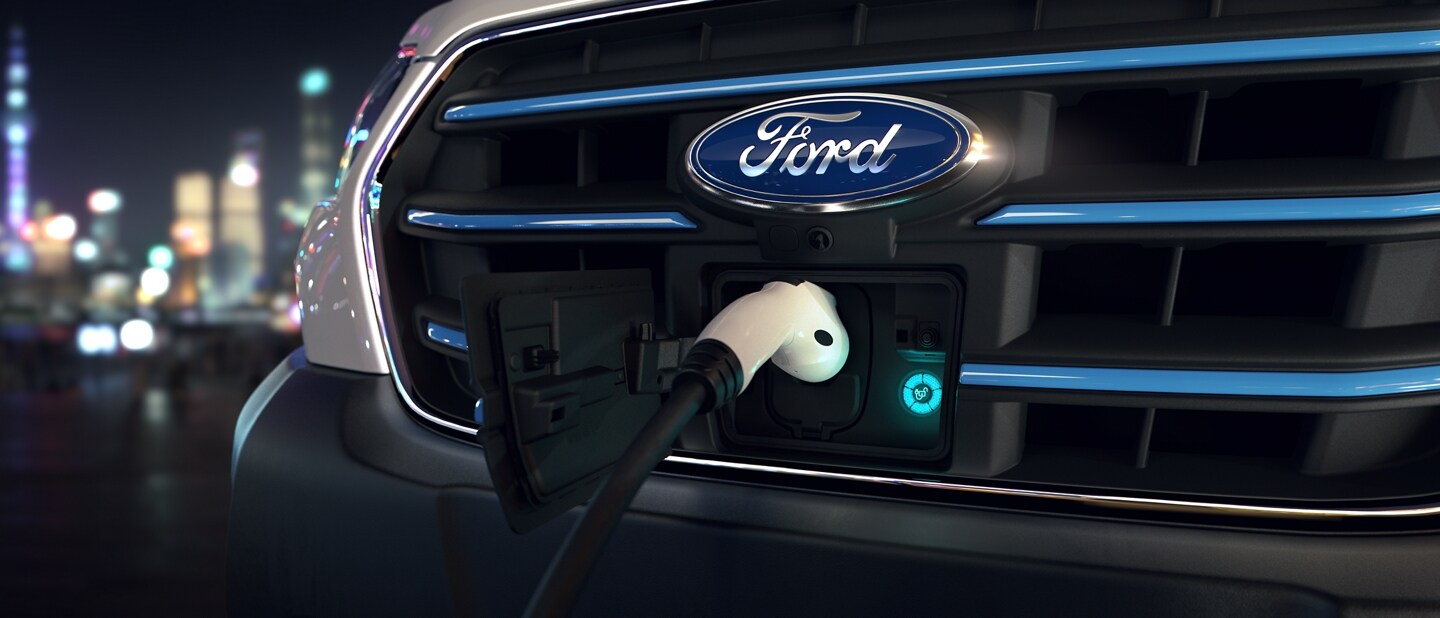 Close-up shot of the grille with a charger plugged in for the 2023 Ford E-Transit™ van
