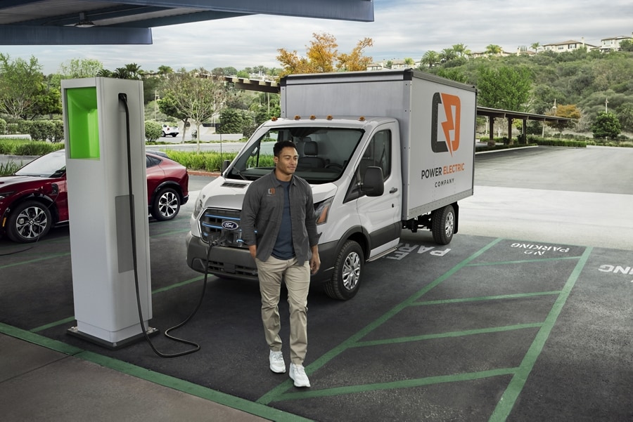 A man is standing in a parking lot while a vehicle is being charged