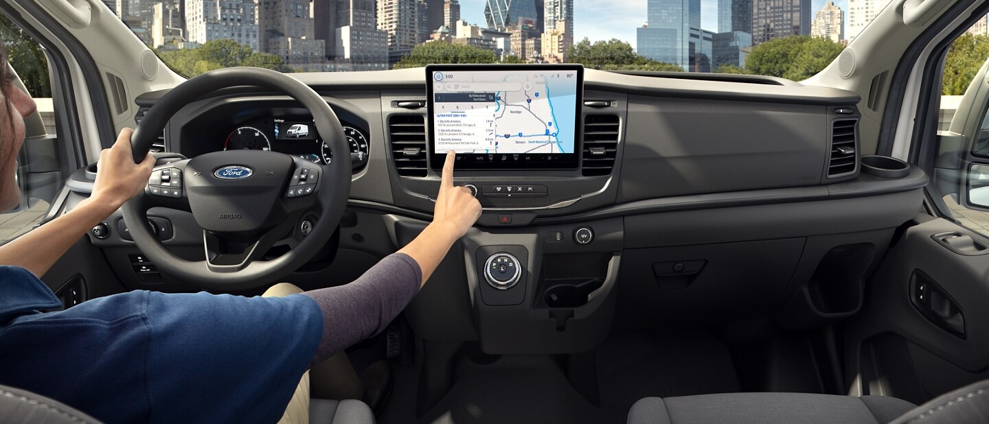 Person sitting in vehicle touching a screen above the centre console