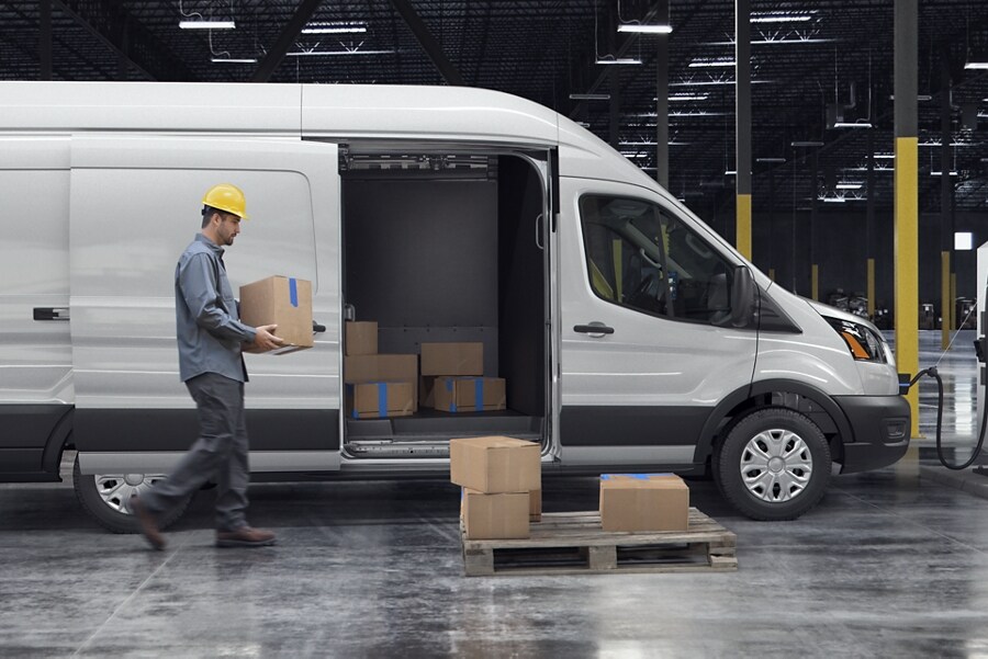 Man lifting boxes into the side door of the 2023 Ford E-Transit™ van