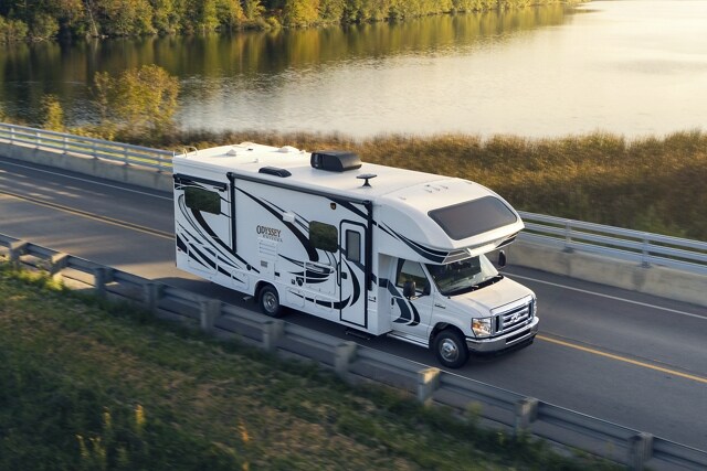 2023 Ford E-Series Cutaway with Class C motorhome being driven near a large body of water
