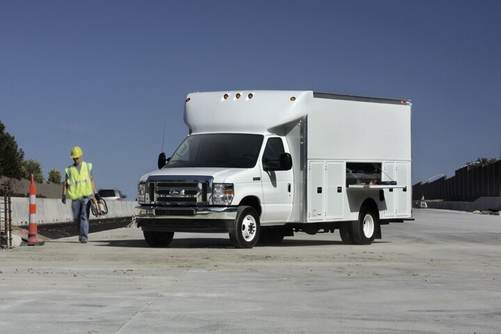A person walking away from a 2024 Ford E-Series dual-rear-wheel Cutaway with contractor’s body upfit