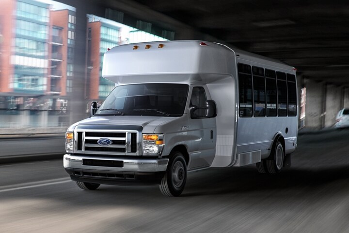 2025 Ford E-Series dual-rear-wheel Cutaway with shuttle bus upfit being driven under a bridge