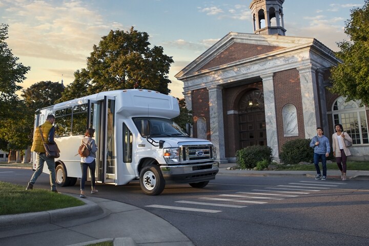 People getting into a 2025 Ford E-Series dual-rear-wheel Cutaway with Shuttle Bus upfit
