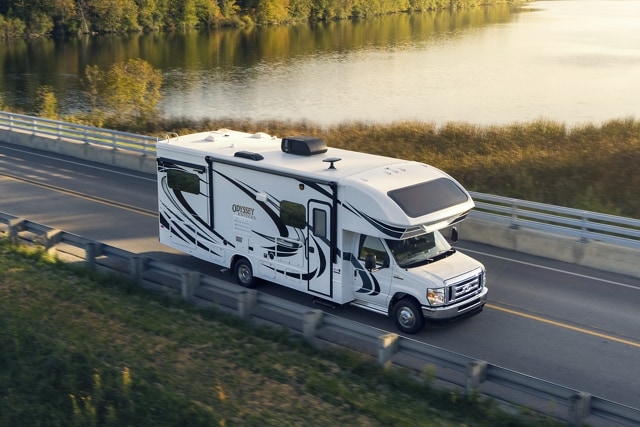 2025 Ford E-Series Cutaway with Class C motorhome being driven near a large body of water