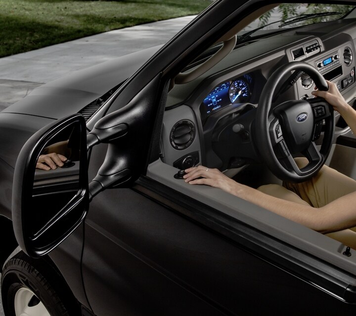 A woman adjusting the available telescoping trailer tow mirrors on the 2026 Ford E-Series Cutaway