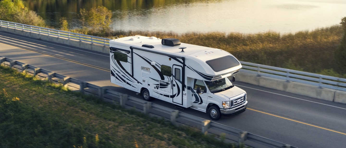 2026 Ford E-Series Cutaway with Class C motorhome being driven near a large body of water