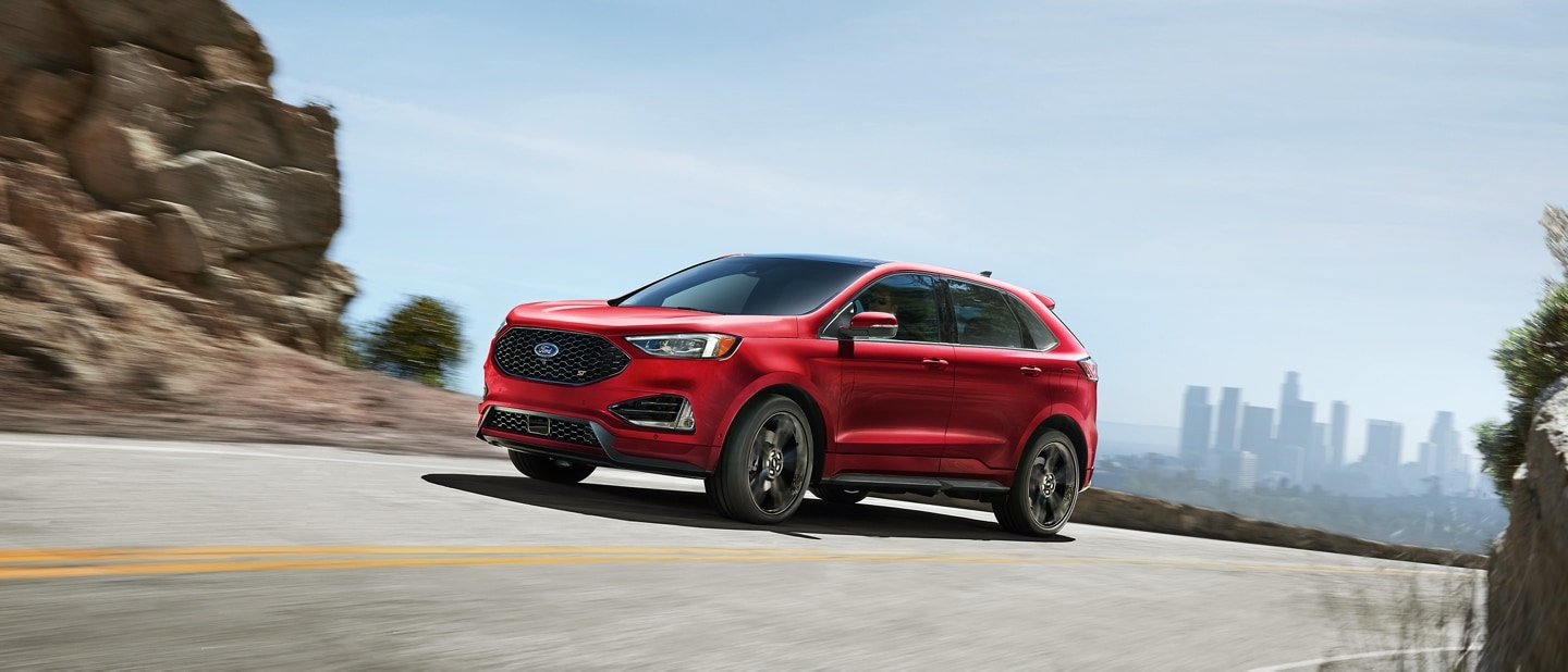 A 2023 Ford Edge ST in Rapid Red being driven on a mountain road