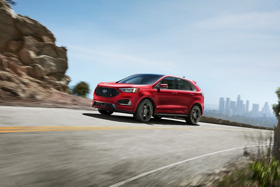 A 2023 Ford Edge ST in Rapid Red being driven on a mountain road