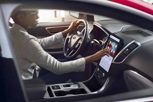 Interior shot of a 2023 Ford Edge® as a woman presses on the touchscreen